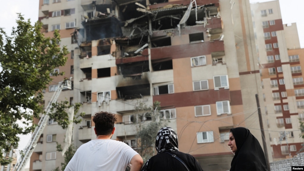 Mọi người nhìn vào một tòa nhà bị hư hại sau cuộc không kích của Israel tại Tehran vào ngày 13 tháng 6.