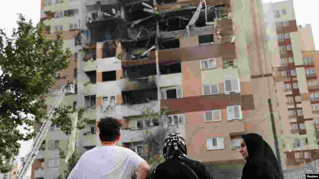 Njerëzit shikojnë një ndërtesë të dëmtuar pas sulmeve izraelite në Teheran, më 13 qershor.