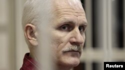 Human rights activist Ales Byalyatski sits in a guarded cage in a courtroom in Minsk during his trial in November 2011.