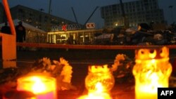شهروندان در برابر فروشگاه سانحه‌دیده جمع شده و به یاد قربانیان شمع روشن کرده‌اند