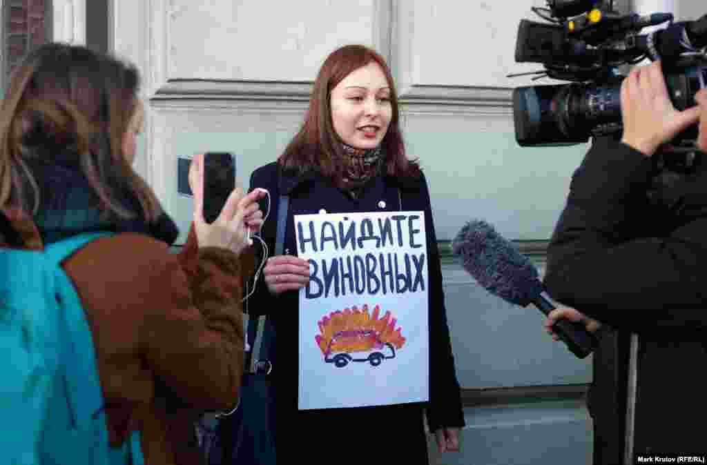 Нападавшие сожгли микроавтобус, на котором журналисты и правозащитники ехали из аэропорта Беслан в Грозный (с плакатом стоит журналист Анастасия Зотова)
