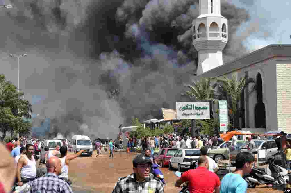 People react after a powerful explosion in the northern Lebanese city of Tripoli. Two explosions went off within minutes of each other, killing at least 12 people. (AFP/Ibrahim Chalhoub)