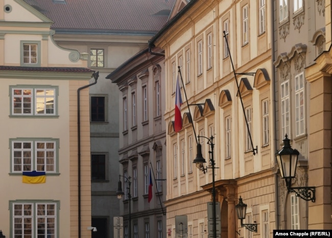 میلۀ خالی پرچم بر ساختمان پارلمان چک در حالی که در سمت چپ یکی از هشت پرچم تازه نصب‌شدۀ اوکراین از دفاتر پارلمان آویزان است