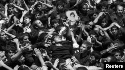 FILE PHOTO: A man is carried at the site in Masala square where the body to Ayatollah Khomeini lies in state, in Tehran, Iran, June 5, 1989. REUTERS/Yannis Behrakis