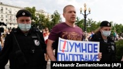 Russian police detain an opposition activist holding a poster featuring the Smart Voting logo during a protest in Moscow last month.