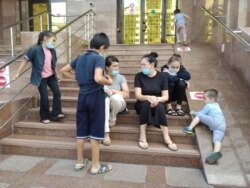 Биліктен көмек сұрап келген екі ана балаларымен бірге сауда және интеграция министрлігі ғимаратының алдында отыр. Нұр-Сұлтан, 22 шілде 2020 жыл.