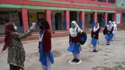 Учитель измеряет температуру учащихся перед входом в школу в Лахоре. 18 января 2021 года.