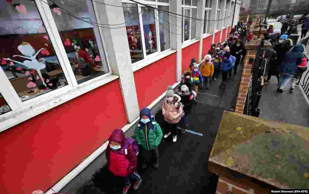 Romanian children line up outside school while waiting to disinfect their hands and enter the building during the first day of school at Cezar Bolliac Secondary School in Bucharest on February 8. (epa-EFE/Robert Ghement)