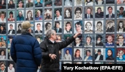 Oamenii se uită la portretele victimelor crizei de la Nord-Ost în timpul unei adunări desfășurate în fața Teatrului Dubrovka din Moscova, în octombrie 2020.