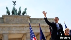 U.S. President Barack Obama waves as he arrives with German Chancellor Angela Merkel to give his speech in front of the Brandenburg Gate on Pariser Platz in Berlin on June 19.