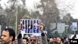 A government supporter holds a poster with a picture of opposition leaders Mehdi Karrubi (left) and Mir Hossein Musavi during a demonstration in Tehran on December 30.