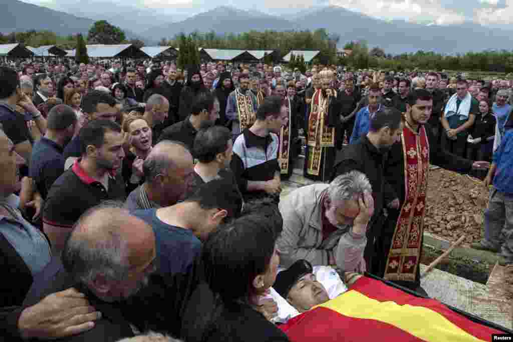 Relatives of Zarko Kuzmanovski, a police officer killed in the operation, mourn next to his coffin draped with the Macedonian flag during his funeral in the village of Brvenica.