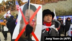 Солтүстік Корея саясатына қарсы наразылық шарасында Ким Чен Ынның портретін ұстап тұрған адам. Каннын, 8 ақпан 2018 жыл.