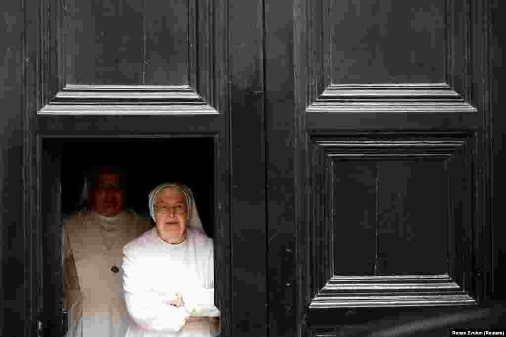 Nuns look out from behind a door as Pierbattista Pizzaballa, the acting Latin Patriarch of Jerusalem, makes his way to the West Bank town of Bethlehem from Jerusalem&#39;s Old City on December 24. (Reuters/Ronen Zvulun)