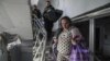 Поранена вагітна жінка йде вниз у пошкодженому від авіаційного удару російських військових пологовому будинку в Маріуполі, 9 березня 2022 року