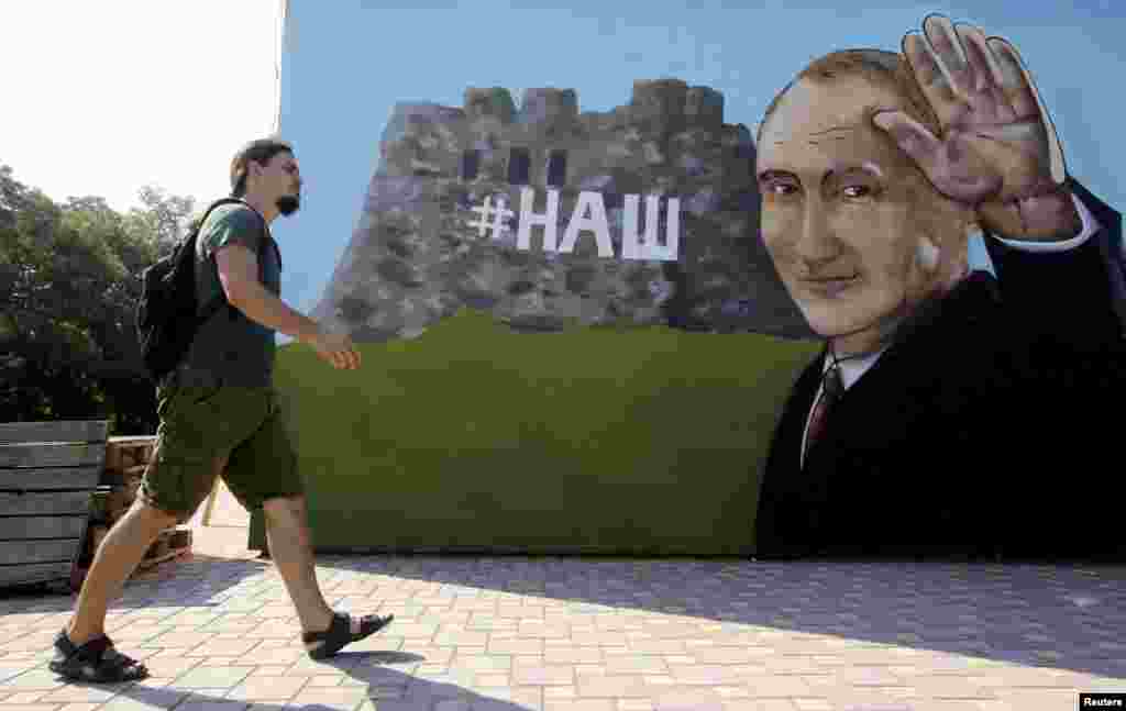 A man walks past graffiti depicting Russian President Vladimir Putin in Simferopol, Crimea, on August 17. (Reuters/Pavel Rebrov)