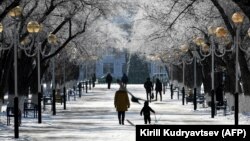 Қыстыгүні көшеде кетіп бара жатқан ересек адам мен бала. Көрнекі сурет.