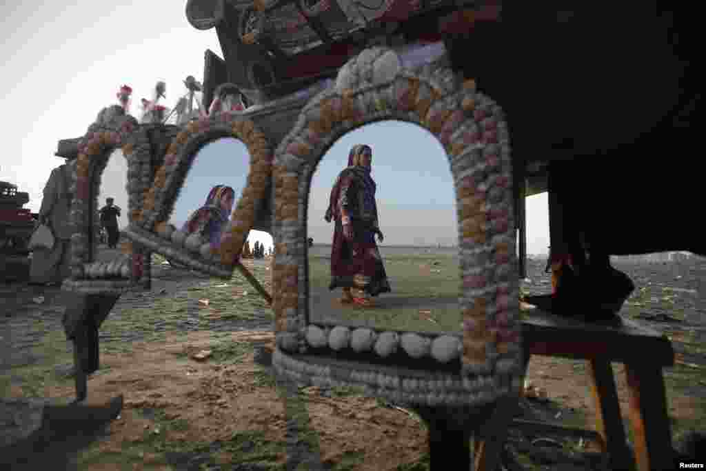 A woman is reflected in mirrors, decorated with sea shells and put up for sale, as she walks along Karachi&#39;s Clifton Beach. (Reuters/Athar Hussain)