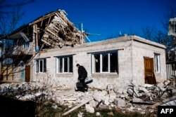 Un om își scoate lucrurile din casa distrusă de bombardamente lângă Donețk, 6 nov.