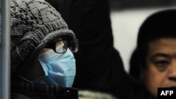 A women wears a mask while on the Beijing subway.