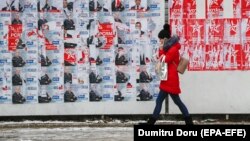 A girl talks on her mobile phone while passing a panel with campaign posters in downtown Chisinau, Moldova (February 13, 2019)