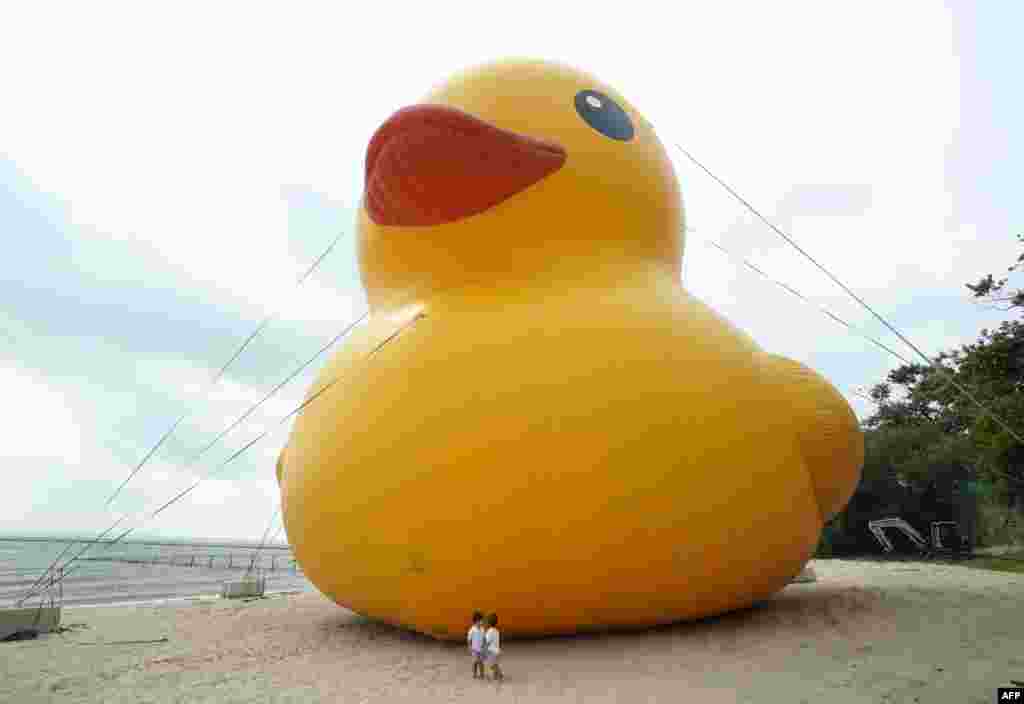 Djeca stoje pored &quot;najveće gumene patke na svijetu&quot; na plaži Rye Playland u Ryeu, New York, 17. avgusta. Patka visoka 19 metara, po imenu &quot;Mama Duck&quot;, provodi vikend na plaži povodom proslave Ljetnih dana pataka.