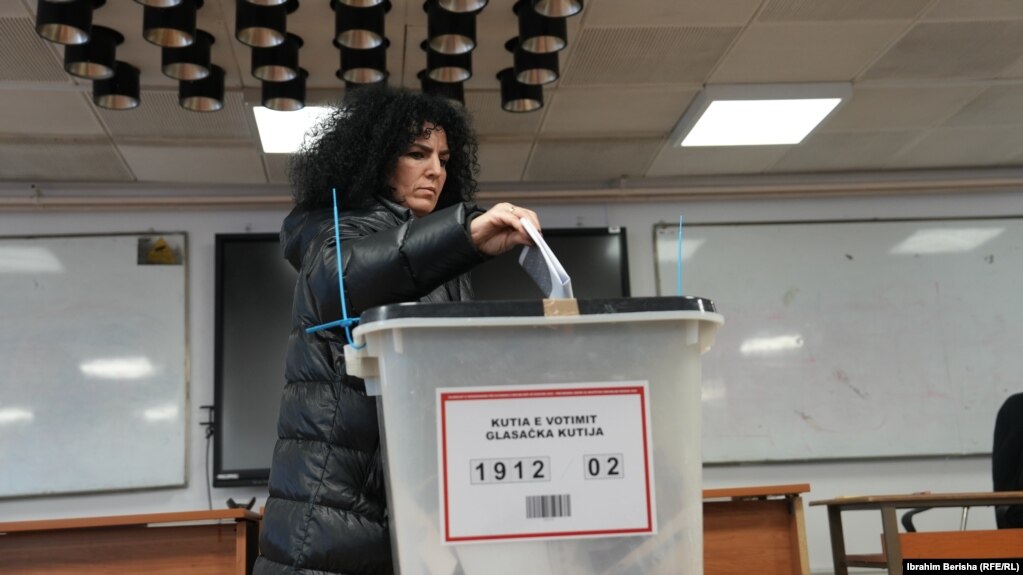 Një grua hedh votën në kutin e votimit pasi votoi në zgjedhjet e parakohshme parlamentare të Kosovës në një qendër votimi në Prishtinë.