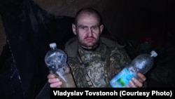 Валентин Товстоног з пляшками води, яку військові набрали в калюжах після дощу.