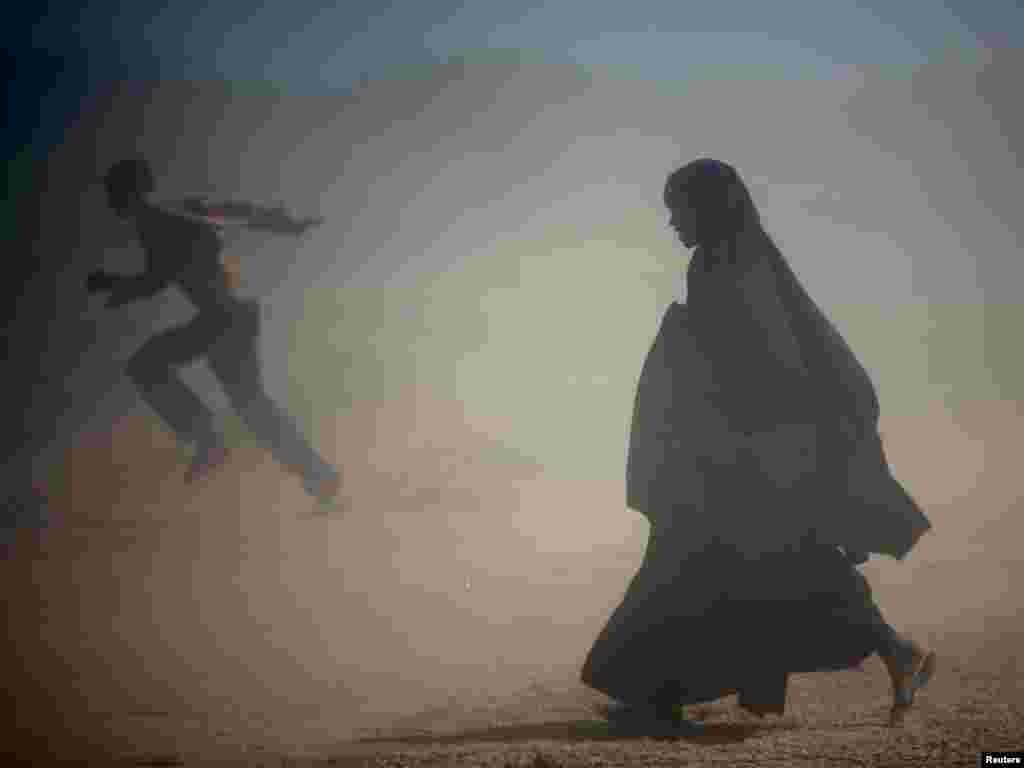 Somali refugees run from the dust at Ifo camp near Dadaab, about 80km (50 miles) from Liboi on the border with Somalia in north-eastern Kenya, January 8, 2007. Aid agencies are operating three large refugee camps in Dadaab where about 160,000 Somali refugees are held and said they could provide more staff to help Kenya with any new influx. REUTERS/Radu Sigheti 