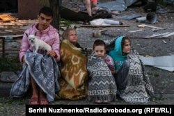 Patru copii stau ghemuiți, împreună cu câinele lor, pe marginea străzii în urma atacului rusesc asupra Kievului din noaptea de miercuri spre joi, 28 august 2025.