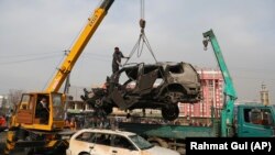 Afghan security personnel oversee the removal of damaged vehicles after a bombing attack in Kabul on December 20, 2020. 