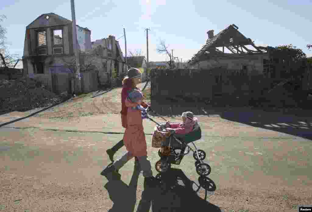 A woman with children walks near houses damaged by recent shelling in the village of Semyonovka near Slovyansk, eastern Ukraine, on October 27. (Reuters/Vasily Fedosenko)