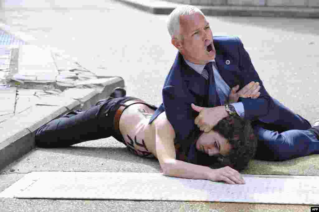 A security guard pins a Femen activist to the ground after she and other activists tried to stop the car of Tunisian Prime Minister Ali Larayedh from leaving the EU commission building in Brussels. They shouted "Free Amina!" -- a reference to Amina Sboui, a teenage anti-Islamist feminist who is being held in a Tunisian jail. (AFP/Georges Gobet)