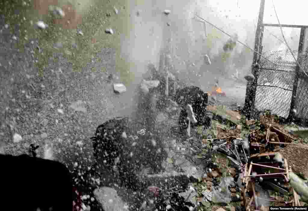 Moments after firing the RPG, the same rebels are caught in a hail of shrapnel and concrete after a tank shell slammed into the wall above them.