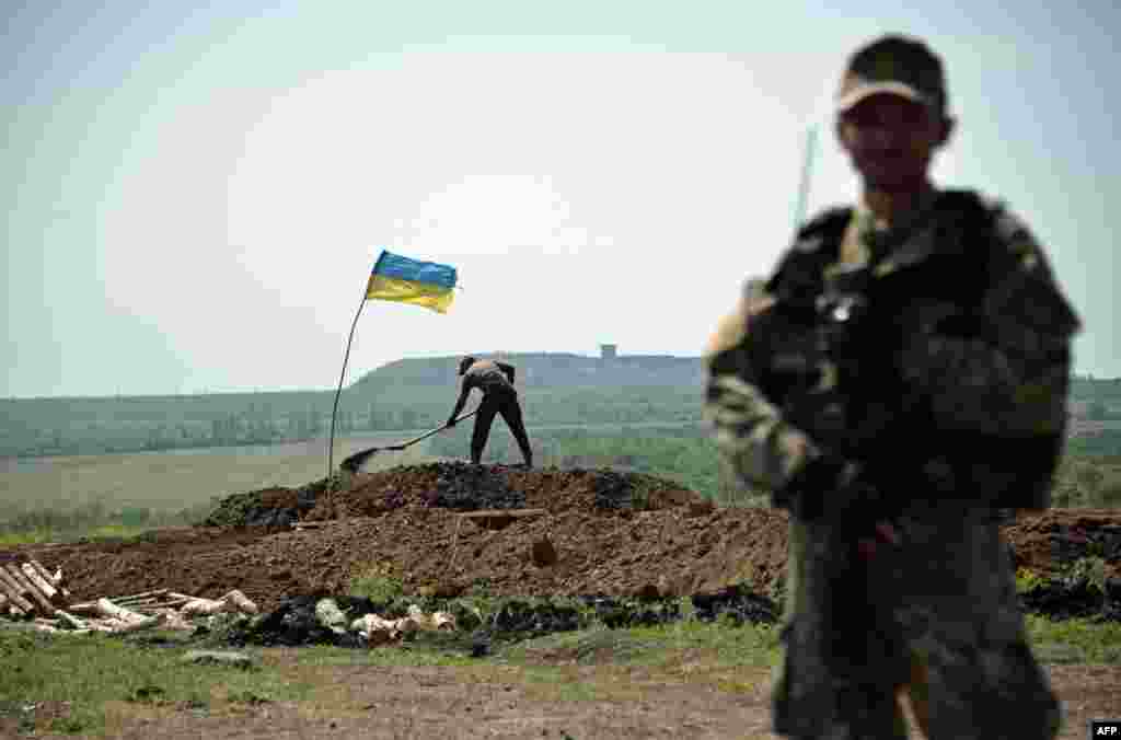 A Ukrainian serviceman stands at a position as workers dig trenches on the front line of fighting against pro-Russian separatist in eastern Ukraine, near Artemivsk, on May 26.