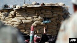 Blokpostga hujum qilgan yaralanga ayol ko'rsatkich barmog'ini osmonga ko'rsatmoqda.