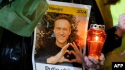 Një person e mban një qiri dhe një portret të liderit të ndjerë rus, Alexei Navalny, i cili vdiq në një burg rus në Arktik, Zagreb, Kroaci, 23 shkurt 2024.