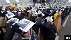 Участники Евромайдана держат над головой плакаты с портретом президента Украины со словами "Виктор, мне тебя жаль"