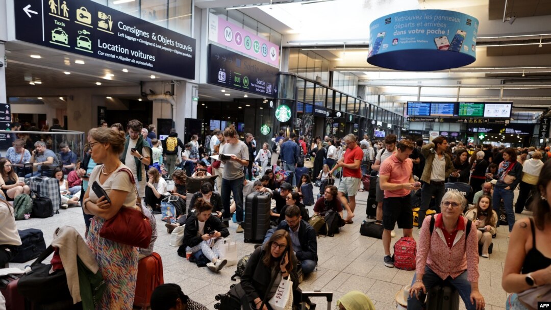 Pasagerii așteaptă plecarea trenurilor în gara Montparnasse, Paris, pe 26 iulie 2024, în timp ce rețeaua feroviară de mare viteză din Franța a fost afectată de incendieri care au perturbat sistemul de transport.