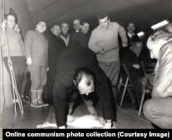 A Romanian diplomat is whipped on the backside by Ceausescu while crouching over the carcass of a hare. The photo was taken during a hunting trip with the heads of Romania’s diplomatic missions in 1969.