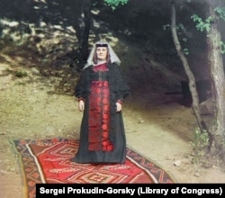 A Georgian woman poses in her finery at an unknown location.