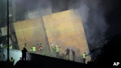 Rescuers gather as smoke rises from a collapsed building at the site of an Israeli air strike in Beirut's southern suburbs on September 27.