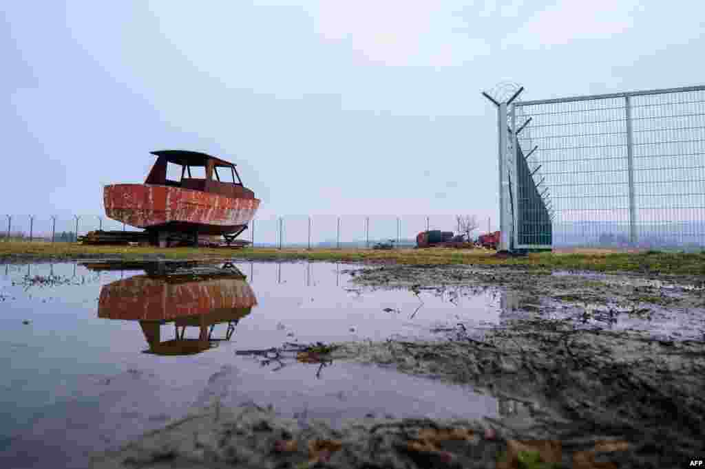 A picture taken near the village of Gibina, shows the hull of a boat next to a fence set up along the Slovenian-Croatian border. (AFP/Jure Makovec)