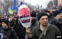 A protester carries a balloon with a picture showing Ukrainian President Petro Poroshenko and the words "Poroshenko is not my president" during a mass march and rally in Kyiv on February 18.