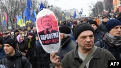 A protester carries a balloon with a picture showing Ukrainian President Petro Poroshenko and the words "Poroshenko is not my president" during a mass march and rally in Kyiv on February 18. 