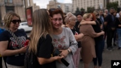 Családtagok és támogatók vigasztalják egymást a kijevi Majdanon július 29-én, az orosz megszállás alatt álló ukrajnai Olenyivka börtönépület elleni támadás első évfordulóján, amely több tucat ukrán hadifogoly halálát okozta