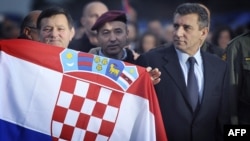 Mladen Markac (left) holds a national flag next to Ante Gotovina (right) upon their arrival at Zagreb airport on November 16.