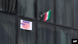 پرچم جمهوری اسلامی و یک پوستر ضد آمریکایی روی پنجرۀ یک ساختمان دولتی در مقابل سفارت سابق آمریکا در تهران، ۱۳ آبان ۱۴۰۲
