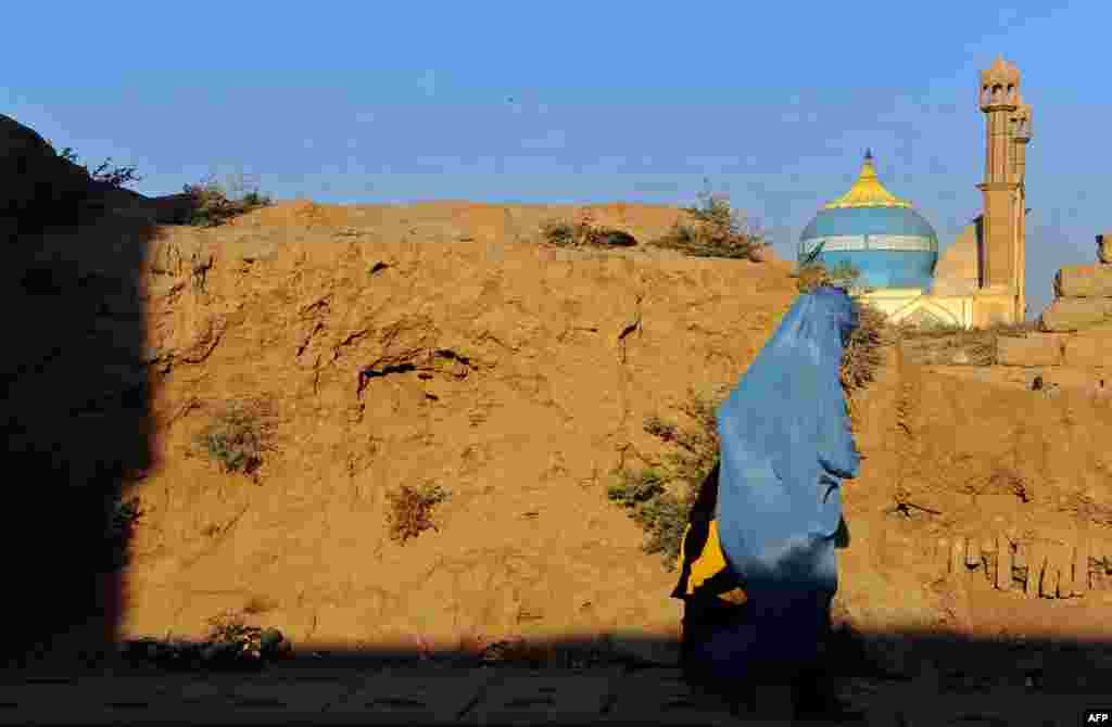 A burqa clad Afghan woman walks along a road in Herat Province. (AFP/Aref Karimi)