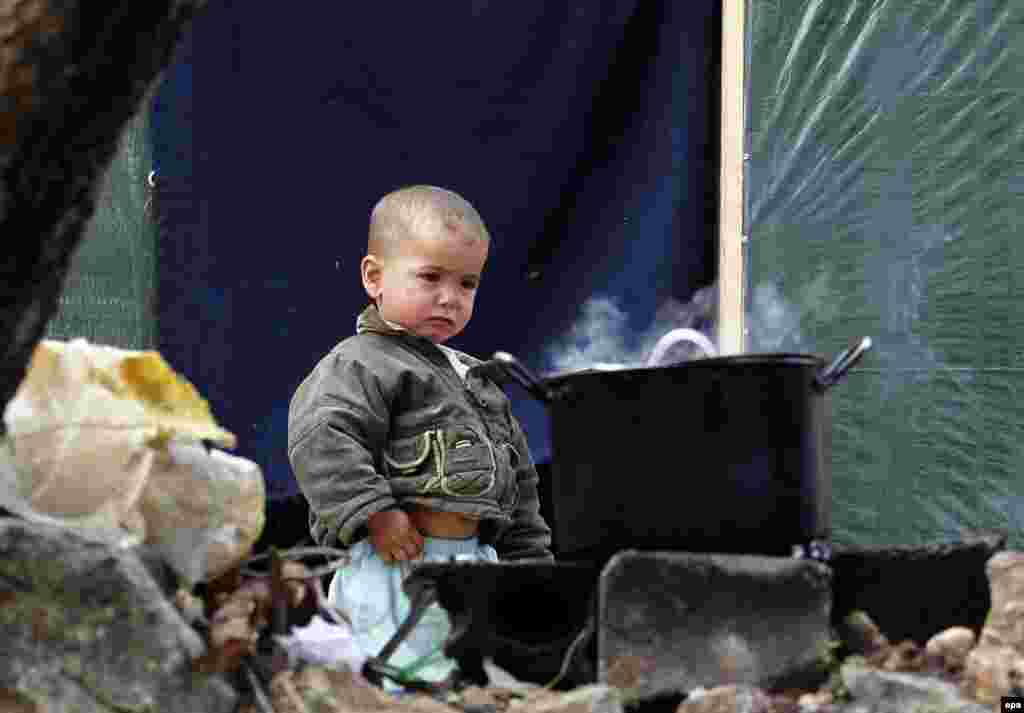 A Syrian refugee's child stands next to a cooking pan at a refugee camp in Ketermaya village, near Sidon, Lebanon, on November 26. EPA/Nabil Mounzer